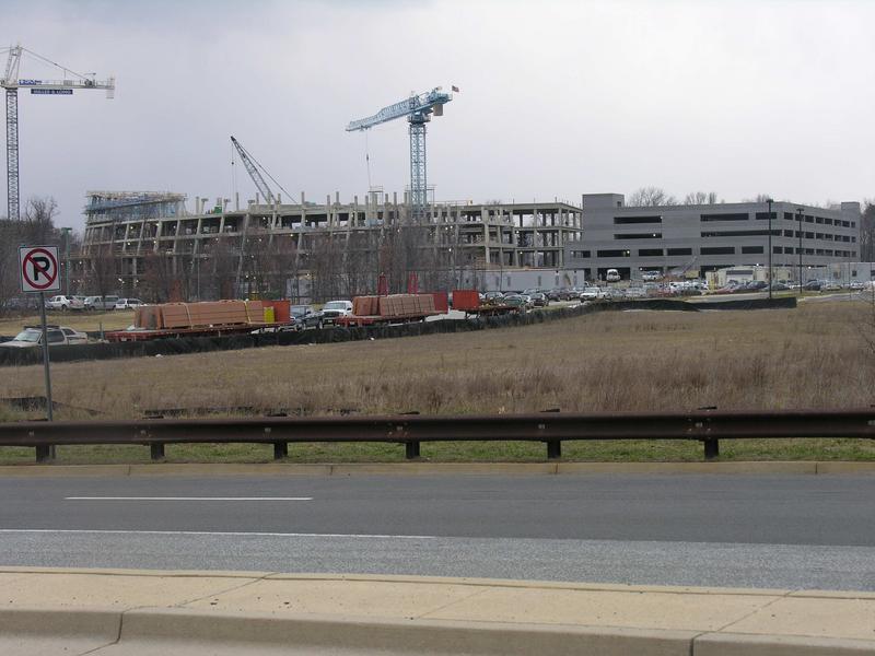 Close up view of construction site taken from River Road. Note flat bed trucks parked along entrance road carrying wall segments.