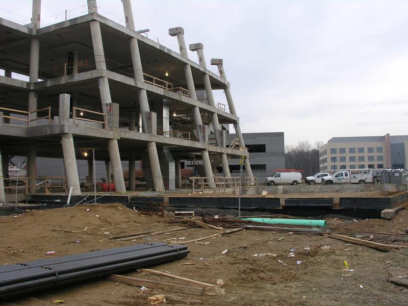 Southeast corner of building with auditorium foundation in front, parking garage in rear and UMD building to the right.