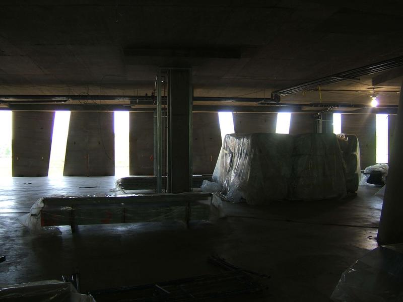 Metal studs and insulation are piled on second floor in preparation for wall layout. Note column in center of picture is surrounded by studs