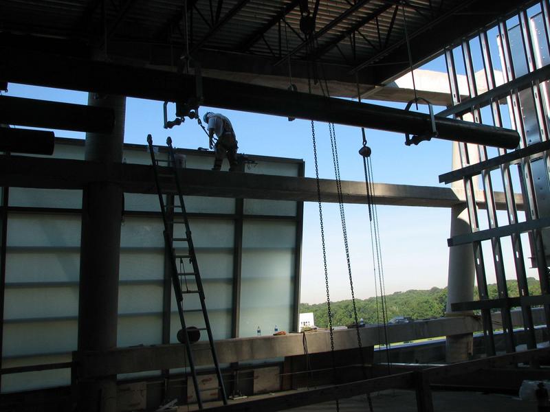 Workers install windows on fifth level; note they are translucent, not transparent as on levels one through four