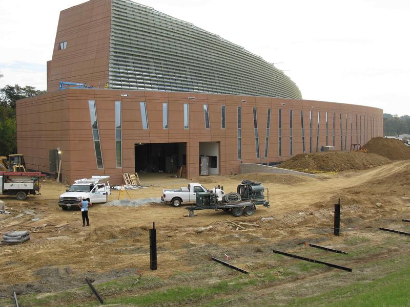 West side of building with loading dock and two story data center wing in the foreground. Black posts in foreground mark the property boundary.