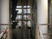 In the atrium, the floating stairs can be seen; additional scaffolding is being installed and workers are preparing to install hand rails.