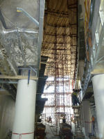 A view from the ground floor at the apex of the Atrium looking upwards. Note, the wooden platform is installed at the 4th floor, where they are currently installing the railing braces. For appreciation of the Atrium ceiling height, it is one story above the wooden platform. 
