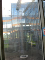 View through window of rooftop waterfall. Water draining from roof after a rain follows the cables down to a splash basin
