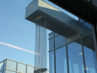 Rooftop waterfall. Water draining from roof after a rain follows the cables down to a splash basin.